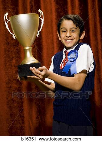 Stock Image - Boy with blue ribbon and trophy cup smiling. Fotosearch