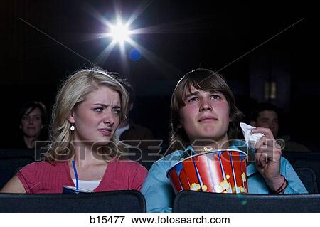 Boy with tissues crying at movie theater with girl watching View Large Photo Image Stock Photo - Boy with tissues crying at movie theater with girl watching. Fotosearch
