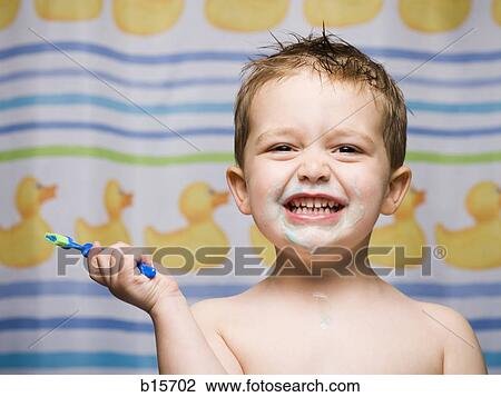 Stock Image - Boy with toothbrush in bathroom smiling. Fotosearch