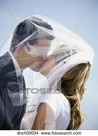 Picture - Bride and groom kissing under veil. Fotosearch