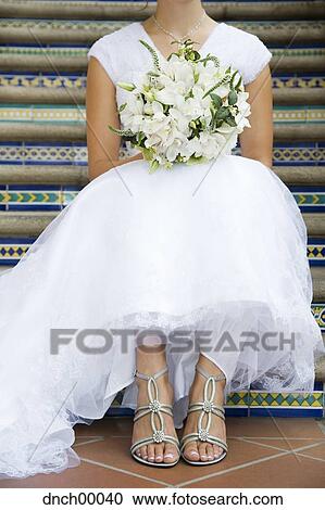 Bride sitting on steps with bouquet neck down View Large Photo Image Stock Image - Bride sitting on steps with bouquet neck down. Fotosearch