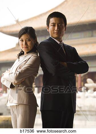 Businessman and woman standing with arms crossed and backs together with pagoda in background View Large Photo Image Stock Photograph - Businessman and woman standing with arms crossed and backs together with pagoda in background. Fotosearch