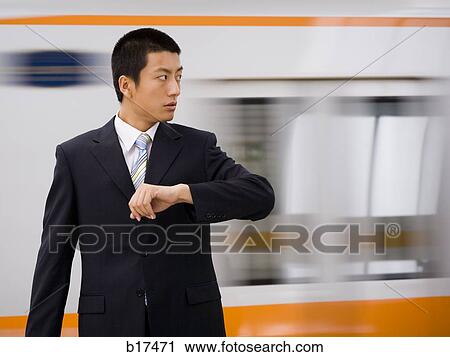 Stock Image - Businessman checking watch with subway in motion in background. Fotosearch