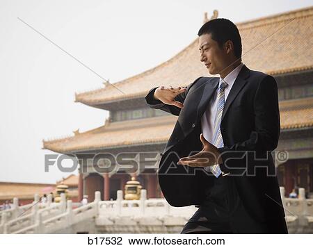 Stock Image - Businessman doing tai chi outdoors smiling. Fotosearch