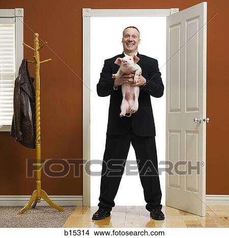 Businessman holding piglet at home View Large Photo Image Picture - Businessman holding piglet at home. Fotosearch