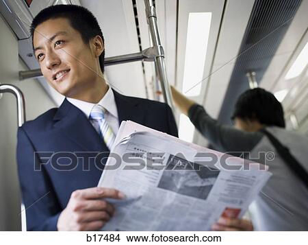 Businessman on subway or bus with newspaper smiling View Large Photo Image Picture - Businessman on subway or bus with newspaper smiling. Fotosearch