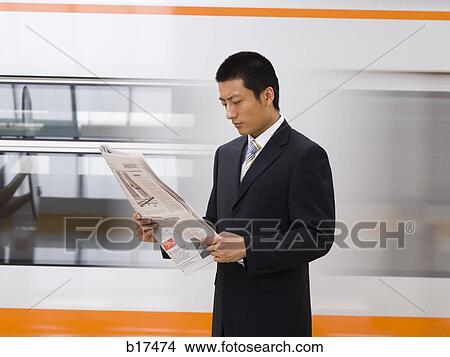 Businessman reading newspaper with subway in background View Large Photo Image Picture - Businessman reading newspaper with subway in background. Fotosearch