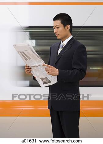 Businessman reading newspaper with subway in background View Large Photo Image Stock Image - Businessman reading newspaper with subway in background. Fotosearch