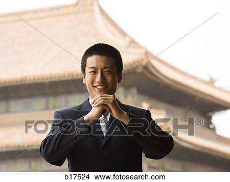 Businessman smiling with hands in greeting with pagoda in background View Large Photo Image Picture - Businessman smiling with hands in greeting with pagoda in background. Fotosearch