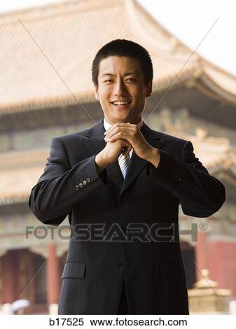 Businessman smiling with hands in greeting with pagoda in background View Large Photo Image Stock Photography - Businessman smiling with hands in greeting with pagoda in background. Fotosearch