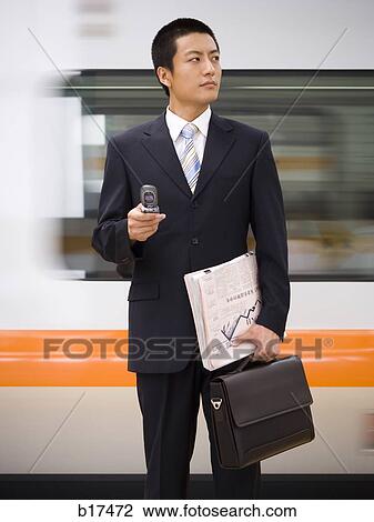Businessman with cell phone and newspaper with subway in background View Large Photo Image Stock Image - Businessman with cell phone and newspaper with subway in background. Fotosearch