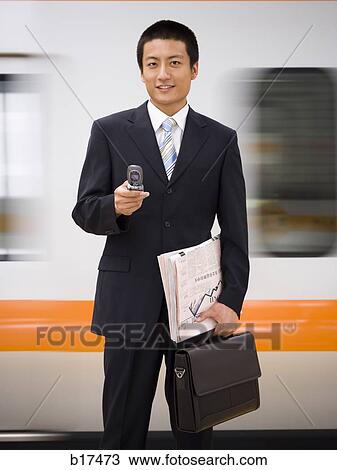 Businessman with cell phone and newspaper with subway in background View Large Photo Image Stock Image - Businessman with cell phone and newspaper with subway in background. Fotosearch