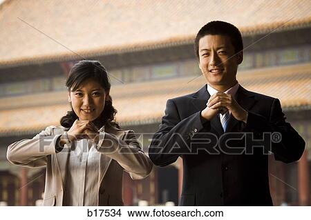 Picture - Businesswoman and man doing tai chi outdoors smiling. Fotosearch