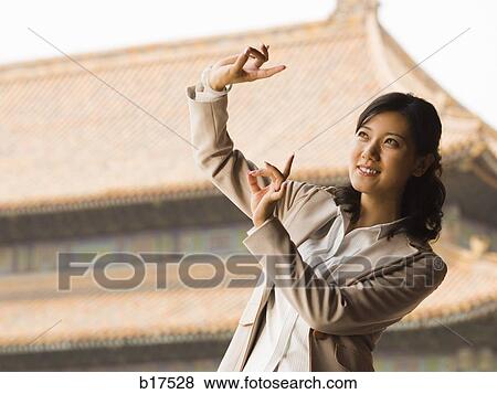 Businesswoman doing tai chi outdoors smiling View Large Photo Image Stock Photo - Businesswoman doing tai chi outdoors smiling. Fotosearch
