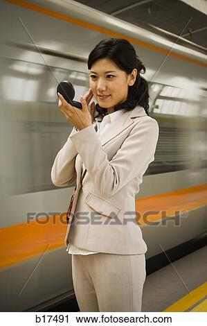 Businesswoman on subway platform smiling and looking in compact mirror View Large Photo Image Stock Image - Businesswoman on subway platform smiling and looking in compact mirror. Fotosearch