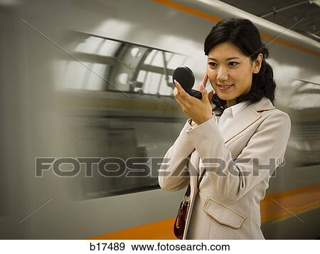 Businesswoman on subway platform smiling and looking in compact mirror View Large Photo Image Stock Photo - Businesswoman on subway platform smiling and looking in compact mirror. Fotosearch