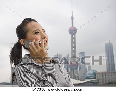 Businesswoman outdoors on cell phone with city skyline in background View Large Photo Image Stock Image - Businesswoman outdoors on cell phone with city skyline in background. Fotosearch