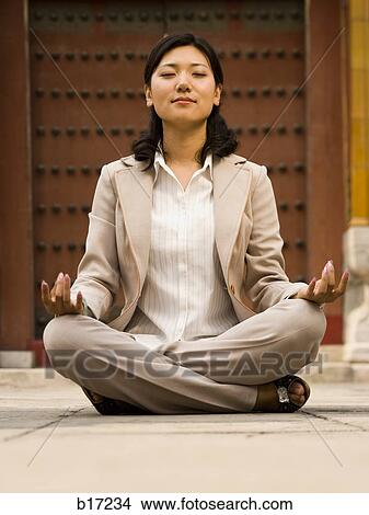 Businesswoman sitting cross legged outdoors meditating View Large Photo Image Picture - Businesswoman sitting cross legged outdoors meditating. Fotosearch