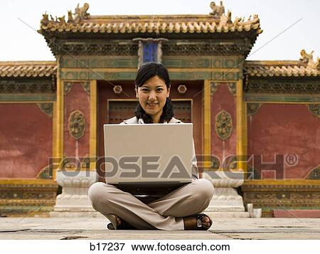 Businesswoman sitting cross legged outdoors with laptop View Large Photo Image Stock Photo - Businesswoman sitting cross legged outdoors with laptop. Fotosearch