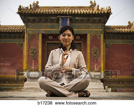 Businesswoman sitting cross legged outdoors meditating View Large Photo Image Stock Photo - Businesswoman sitting cross legged outdoors meditating. Fotosearch