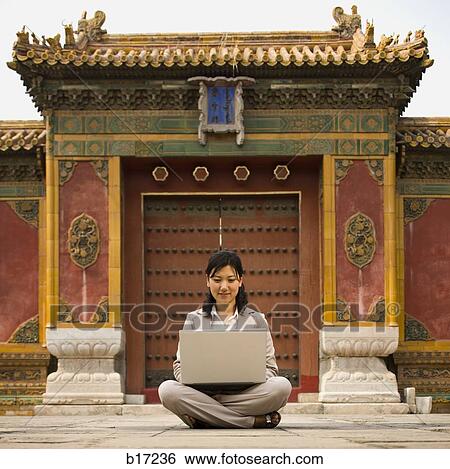 Businesswoman sitting cross legged outdoors with laptop View Large Photo Image Stock Photograph - Businesswoman sitting cross legged outdoors with laptop. Fotosearch
