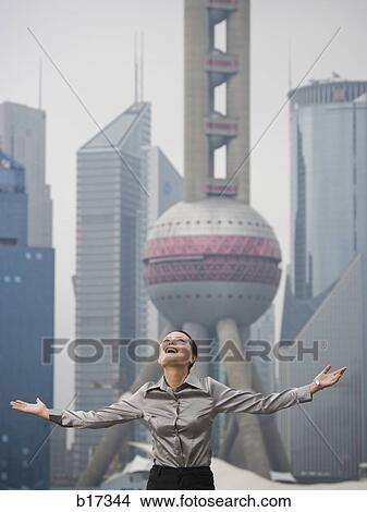Businesswoman smiling outdoors with arms up and city skyline in background View Large Photo Image Picture - Businesswoman smiling outdoors with arms up and city skyline in background. Fotosearch