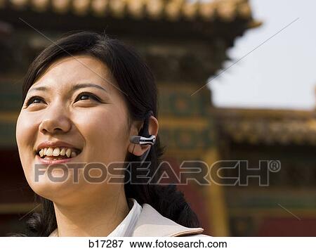 Businesswoman smiling outdoors with headset View Large Photo Image Stock Photo - Businesswoman smiling outdoors with headset. Fotosearch