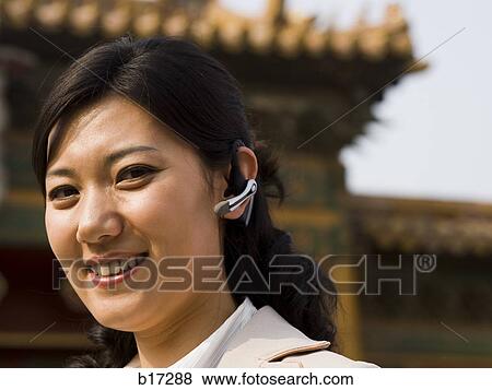 Businesswoman smiling outdoors with headset View Large Photo Image Stock Photo - Businesswoman smiling outdoors with headset. Fotosearch