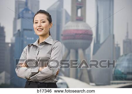 Businesswoman smiling outdoors with arms crossed and city skyline in background View Large Photo Image Stock Photograph - Businesswoman smiling outdoors with arms crossed and city skyline in background. Fotosearch