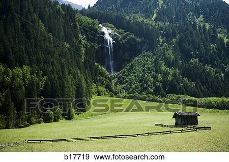 Cabin in valley with mountains and waterfall View Large Photo Image Stock Photo - Cabin in valley with mountains and waterfall. Fotosearch