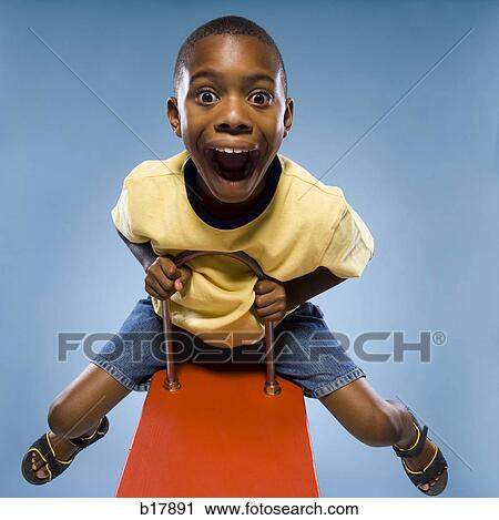 Stock Image - Child riding on a see saw.. Fotosearch