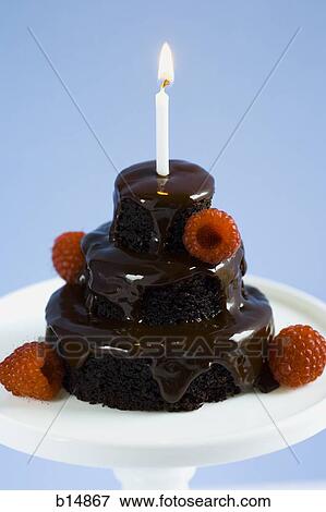 Stock Photo - Chocolate birthday cake with raspberries and candle. Fotosearch