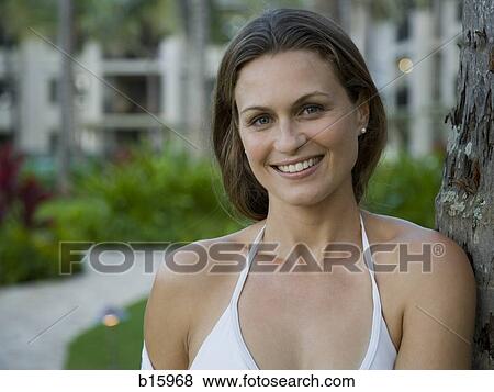 Close-up of woman leaning on tree outdoors smiling View Large Photo Image Stock Photo - Close-up of woman leaning on tree outdoors smiling. Fotosearch