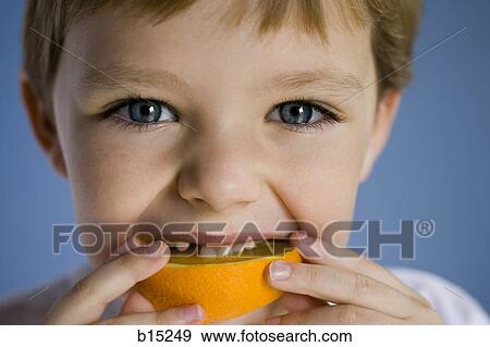 Closeup of boy eating orange wedge View Large Photo Image Stock Photo - Closeup of boy eating orange wedge. Fotosearch