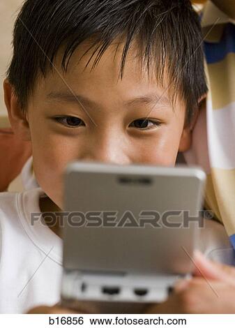 Closeup of boy with handheld electronic device View Large Photo Image Stock Photograph - Closeup of boy with handheld electronic device. Fotosearch