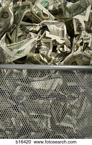 Stock Image - Closeup of crumpled money in waste paper basket. Fotosearch