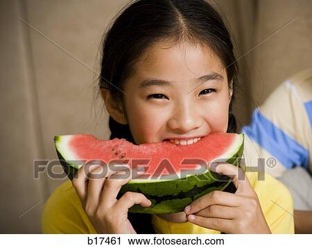 Stock Image - Closeup of girl eating watermelon. Fotosearch