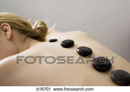 Closeup of topless woman lying down with black stones along spine View Large Photo Image Stock Image - Closeup of topless woman lying down with black stones along spine. Fotosearch