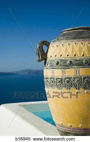 Stock Photography - Closeup of urn with infinity pool with mountains and water in background. Fotosearch