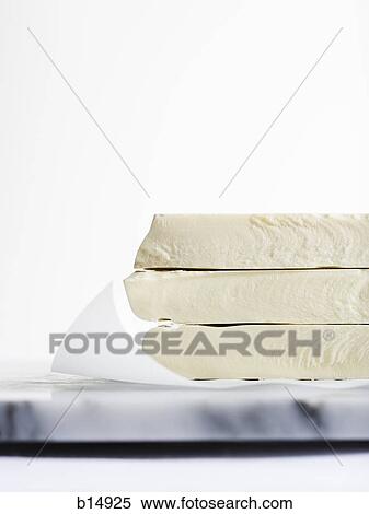 Stock Photography - Closeup of white chocolate cheese or fudge on marble cutting board. Fotosearch