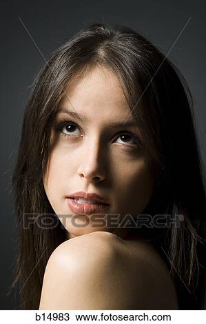 Stock Image - Closeup of woman looking up biting lip. Fotosearch