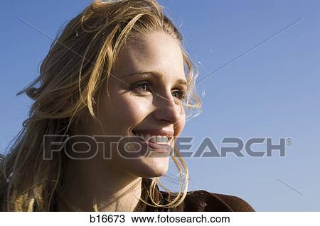 Closeup of woman smiling outdoors with blue sky View Large Photo Image Stock Image - Closeup of woman smiling outdoors with blue sky. Fotosearch