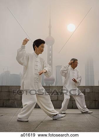 Couple doing tai chi outdoors with city skyline in background View Large Photo Image Stock Photo - Couple doing tai chi outdoors with city skyline in background. Fotosearch