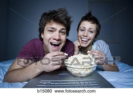 Couple eating popcorn and smiling View Large Photo Image Stock Image - Couple eating popcorn and smiling. Fotosearch