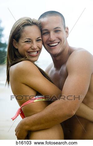 Stock Image - Couple embracing at beach smiling. Fotosearch