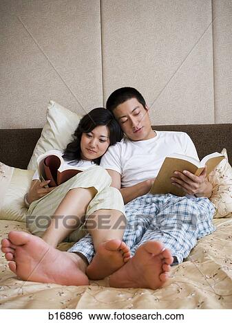 Couple in bed snuggling and reading View Large Photo Image Stock Photograph - Couple in bed snuggling and reading. Fotosearch