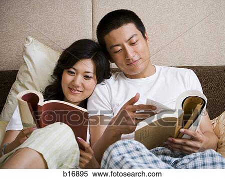 Stock Photography - Couple in bed snuggling and reading. Fotosearch