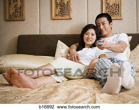 Couple in bed snuggling and watching television View Large Photo Image Stock Image - Couple in bed snuggling and watching television. Fotosearch