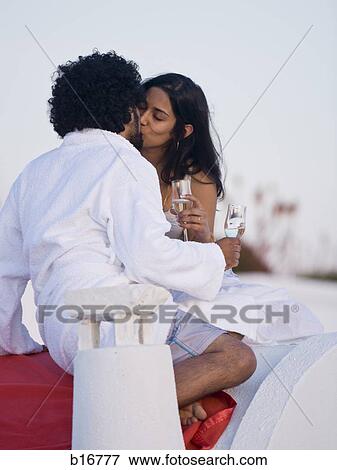 Couple kissing and snuggling outdoors with champagne flutes View Large Photo Image Stock Photo - Couple kissing and snuggling outdoors with champagne flutes. Fotosearch