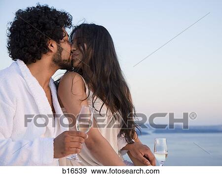 Couple kissing outdoors with champagne flutes View Large Photo Image Stock Photo - Couple kissing outdoors with champagne flutes. Fotosearch